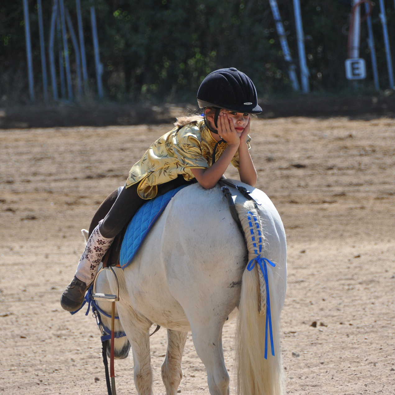 Kisgyerek előre dől a póni hátán